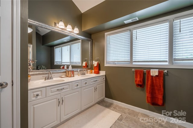 bathroom with double vanity and baseboards