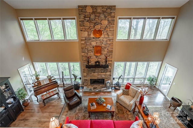 living room with a towering ceiling, wood finished floors, plenty of natural light, and a fireplace