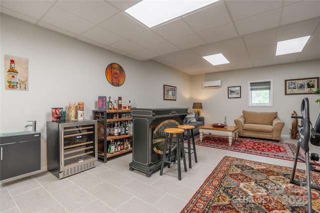 indoor dry bar featuring beverage cooler, a paneled ceiling, a wall unit AC, and light tile patterned floors
