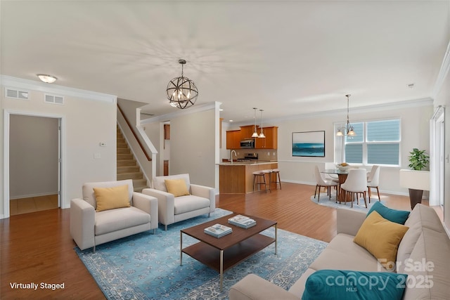 9230 Loch Glen Way, Charlotte, NC 28278 - living room featuring a chandelier, ornamental molding, light wood-style flooring, and stairs