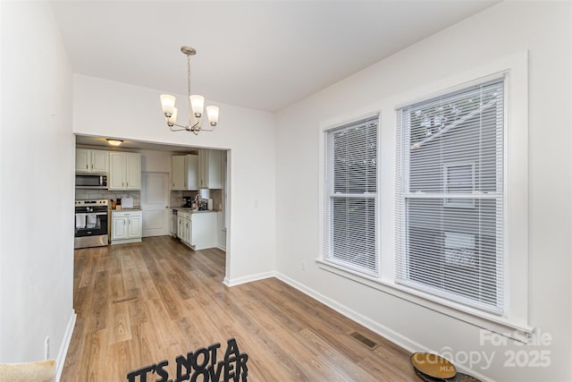 417 S Broad St, Gastonia, NC 28052 - unfurnished dining area with a chandelier, light wood finished floors, and baseboards
