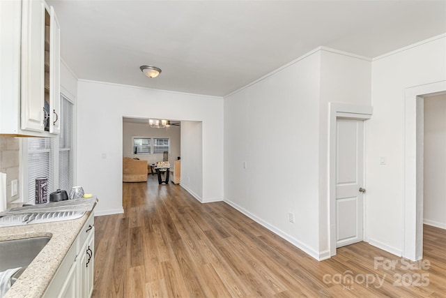 417 S Broad St, Gastonia, NC 28052 - kitchen with light wood-type flooring, light stone counters, crown molding, white cabinets, and glass insert cabinets