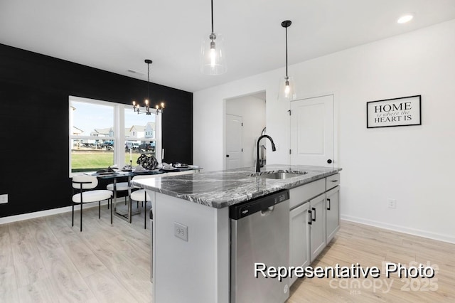 kitchen with dishwasher, a sink, stone counters, light wood-style flooring, and a chandelier