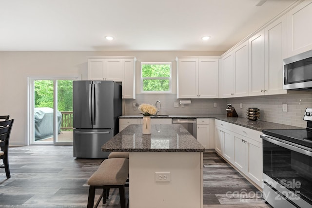 7308 Rothmore St, Charlotte, NC 28215 - kitchen with appliances with stainless steel finishes, a kitchen island, decorative backsplash, a breakfast bar area, and white cabinetry
