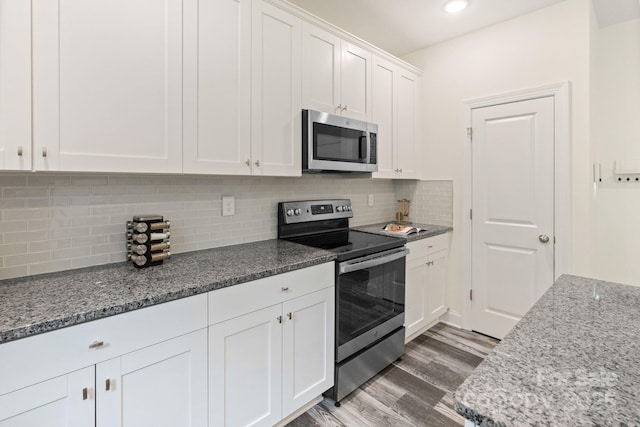 7308 Rothmore St, Charlotte, NC 28215 - kitchen featuring appliances with stainless steel finishes, white cabinetry, wood finished floors, backsplash, and stone counters