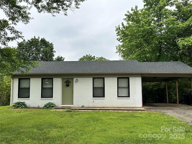 single story home with brick siding, a carport, a front lawn, and driveway