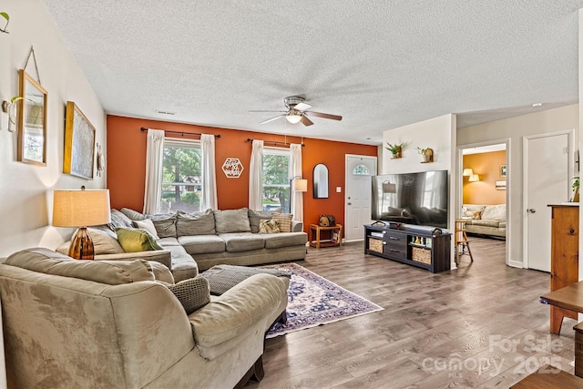 living area featuring a ceiling fan, a textured ceiling, and wood finished floors