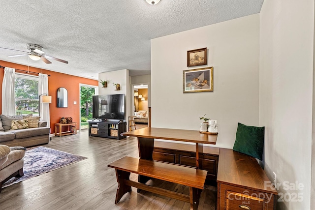 living area with a textured ceiling, ceiling fan, and wood finished floors