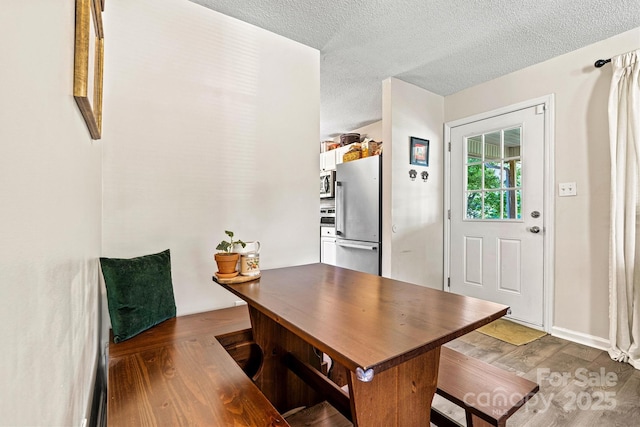 dining space with wood finished floors and a textured ceiling