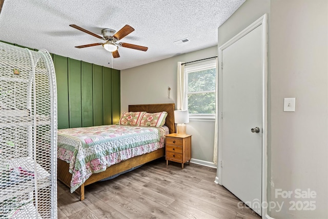 bedroom with wood finished floors, ceiling fan, a textured ceiling, and baseboards