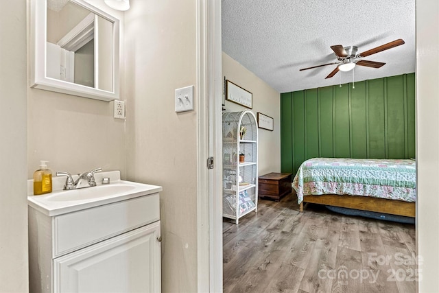bedroom featuring light wood-style floors, a sink, a textured ceiling, and a ceiling fan