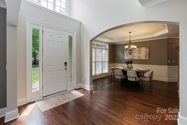 9433 Wallace Pond Dr, Huntersville, NC 28078 - foyer with arched walkways, dark wood-style floors, a tray ceiling, a chandelier, and ornamental molding
