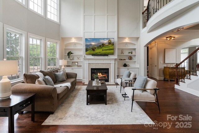 9433 Wallace Pond Dr, Huntersville, NC 28078 - living room with a towering ceiling, arched walkways, built in shelves, dark wood-style floors, and a glass covered fireplace