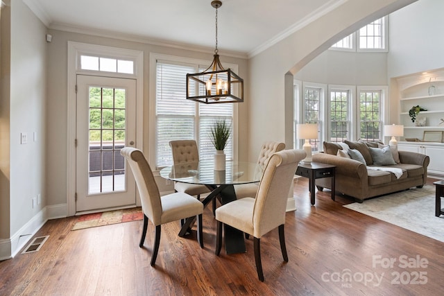 9433 Wallace Pond Dr, Huntersville, NC 28078 - dining area featuring a chandelier, wood finished floors, crown molding, arched walkways, and baseboards