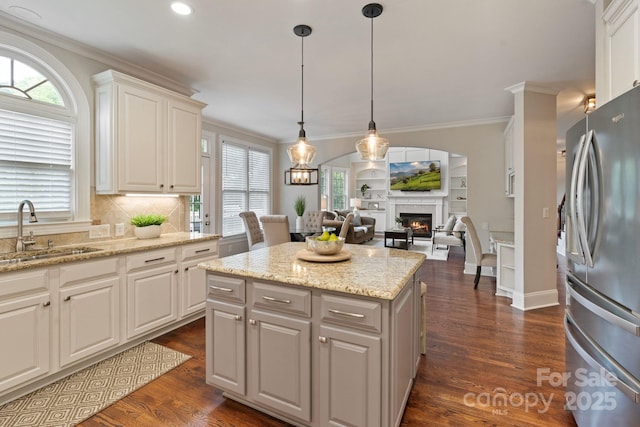 9433 Wallace Pond Dr, Huntersville, NC 28078 - kitchen with freestanding refrigerator, a sink, a warm lit fireplace, crown molding, and white cabinets