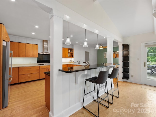 1031 Eldorado Ave, Charlotte, NC 28262 - kitchen featuring wall chimney range hood, a breakfast bar area, freestanding refrigerator, gas stovetop, and recessed lighting