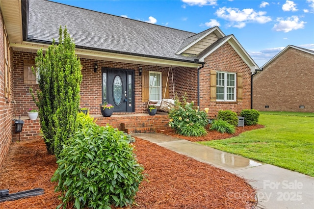 view of front facade with brick siding, a front lawn, and a shingled roof