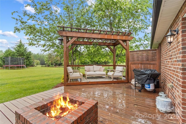 wooden deck featuring an outdoor living space with a fire pit, a trampoline, a yard, a pergola, and grilling area