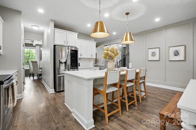 4842 Durneigh Dr, Kannapolis, NC 28081 - kitchen featuring appliances with stainless steel finishes, light countertops, a center island with sink, dark wood-style floors, and white cabinetry