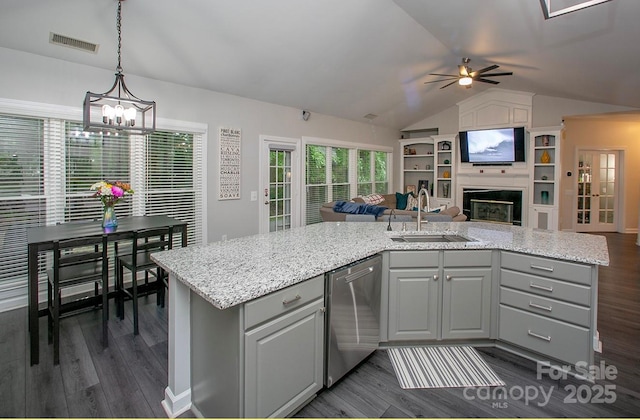 kitchen featuring stainless steel dishwasher, a sink, gray cabinets, open floor plan, and dark wood-style floors