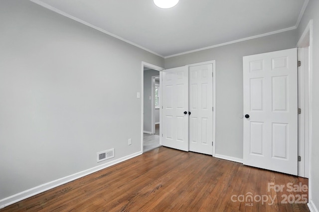 1412 Wembley Dr, Charlotte, NC 28205 - unfurnished bedroom with wood finished floors, baseboards, crown molding, and a closet