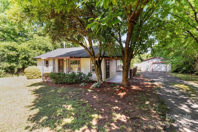 ranch-style home featuring a garage, driveway, an outbuilding, and a porch