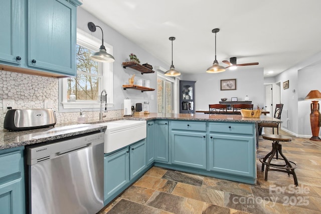 kitchen featuring stainless steel dishwasher, blue cabinetry, a peninsula, a sink, and a ceiling fan