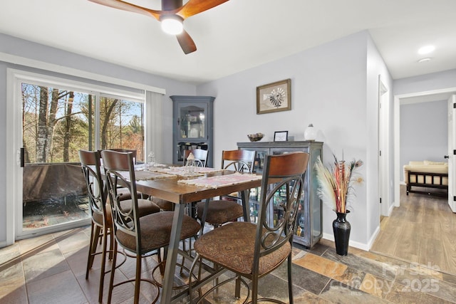 dining room with ceiling fan, baseboards, and stone tile flooring
