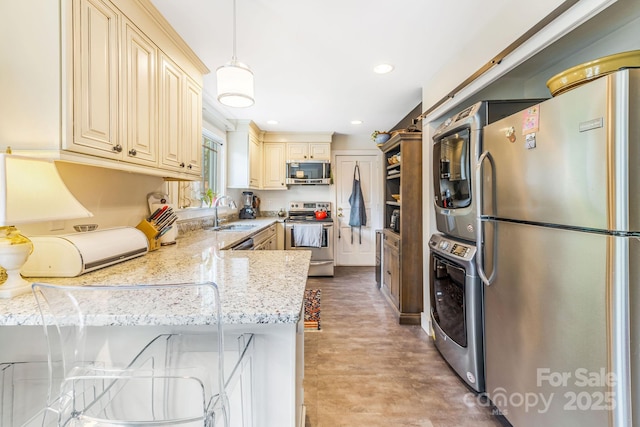 6 Craggy Cir, Asheville, NC 28803 - kitchen featuring appliances with stainless steel finishes, cream cabinets, estacked washer and dryer, light wood-style floors, and recessed lighting