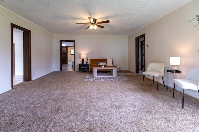 sitting room with carpet flooring, ceiling fan, and crown molding
