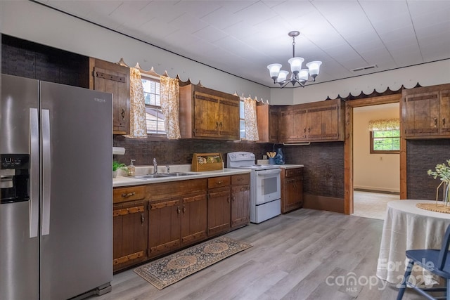 kitchen with stainless steel fridge, electric range, a sink, light countertops, and tasteful backsplash