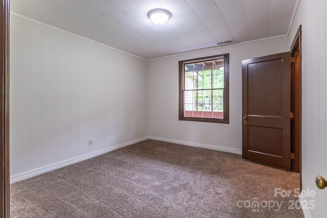 empty room with carpet flooring, crown molding, and baseboards