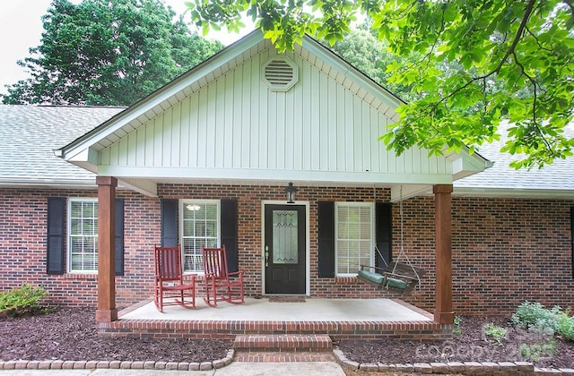1610 Ford St, Charlotte, NC 28216 - view of exterior entry featuring covered porch, brick siding, board and batten siding, and roof with shingles