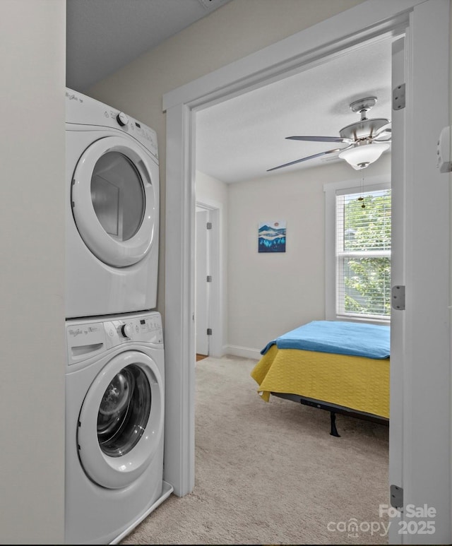 washroom featuring stacked washer / drying machine, carpet flooring, a ceiling fan, and baseboards