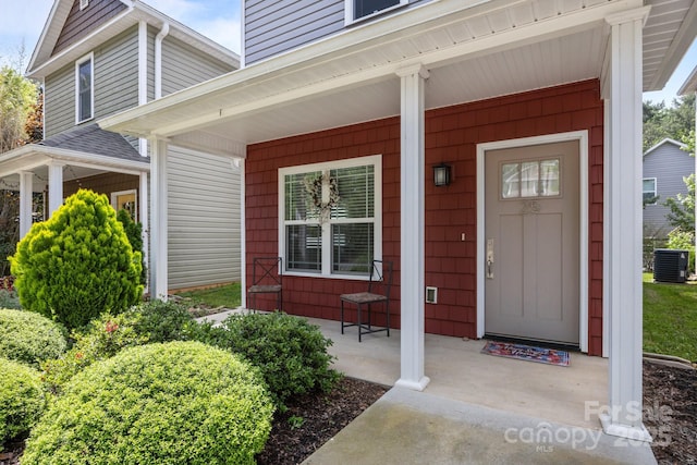 view of exterior entry featuring a porch and central AC
