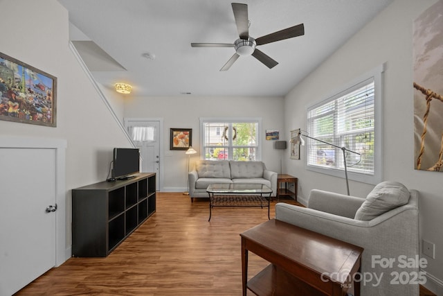 living area featuring wood finished floors, ceiling fan, and baseboards