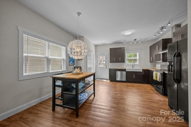 kitchen featuring black appliances, light countertops, a sink, wood finished floors, and baseboards