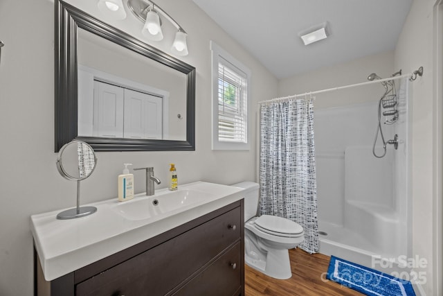 bathroom with toilet, a shower with shower curtain, wood finished floors, and vanity
