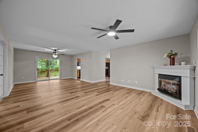16 Lake Forest Ln, Hendersonville, NC 28739 - unfurnished living room with ceiling fan, a glass covered fireplace, light wood-style flooring, and baseboards