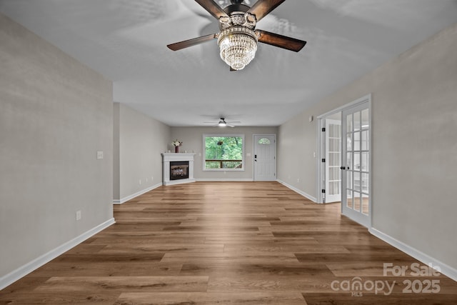 16 Lake Forest Ln, Hendersonville, NC 28739 - unfurnished living room featuring a ceiling fan, wood finished floors, baseboards, french doors, and a fireplace