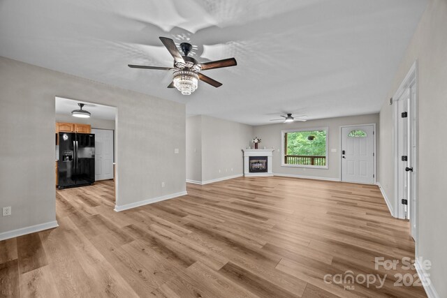 16 Lake Forest Ln, Hendersonville, NC 28739 - unfurnished living room with ceiling fan, baseboards, light wood-style flooring, and a glass covered fireplace