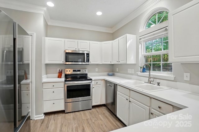 8744 Barrister Way, Charlotte, NC 28216 - kitchen featuring appliances with stainless steel finishes, a sink, light wood-type flooring, white cabinetry, and crown molding