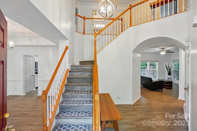 8744 Barrister Way, Charlotte, NC 28216 - stairway featuring arched walkways, wood finished floors, ceiling fan, baseboards, and a high ceiling