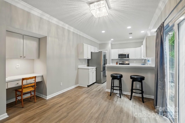 8744 Barrister Way, Charlotte, NC 28216 - kitchen with appliances with stainless steel finishes, ornamental molding, light wood finished floors, a peninsula, and a breakfast bar