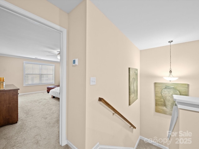 stairs with carpet floors, ceiling fan, and baseboards