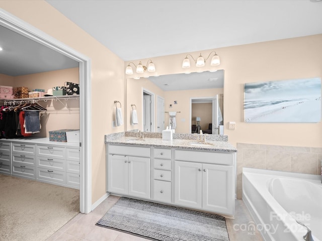bathroom with double vanity, a walk in closet, a garden tub, and tile patterned flooring