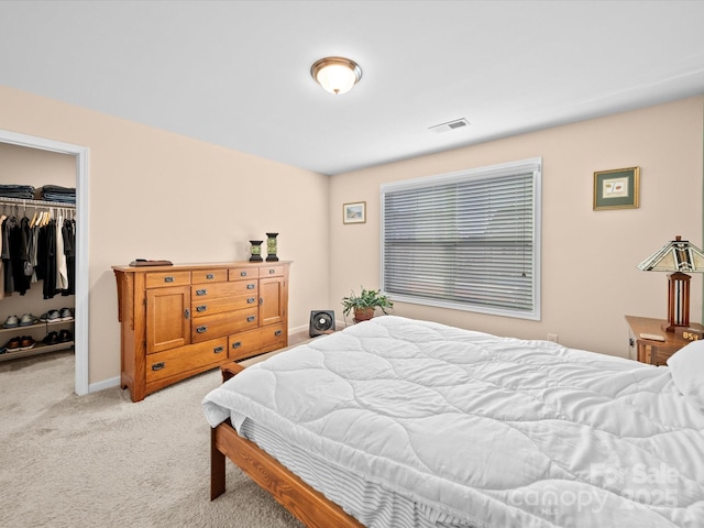 bedroom featuring light colored carpet, a walk in closet, a closet, and baseboards