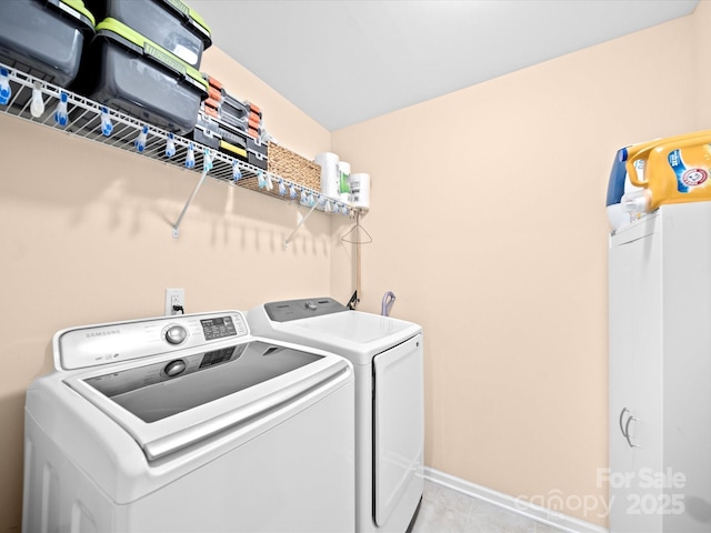 washroom featuring washing machine and dryer, light tile patterned floors, and baseboards