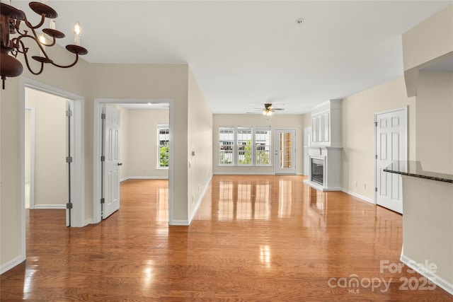 14853 Santa Lucia Dr, Charlotte, NC 28277 - unfurnished living room with a ceiling fan, a fireplace, a chandelier, light wood finished floors, and baseboards