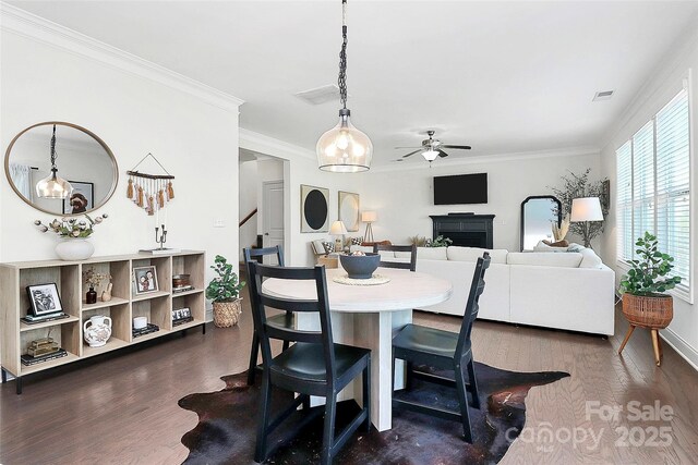 8916 Inverness Bay Rd, Charlotte, NC 28278 - dining space featuring ceiling fan, a fireplace, dark wood-style flooring, stairs, and ornamental molding